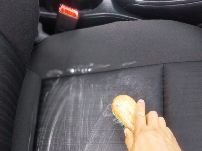 a hand holding a brush on a car seat